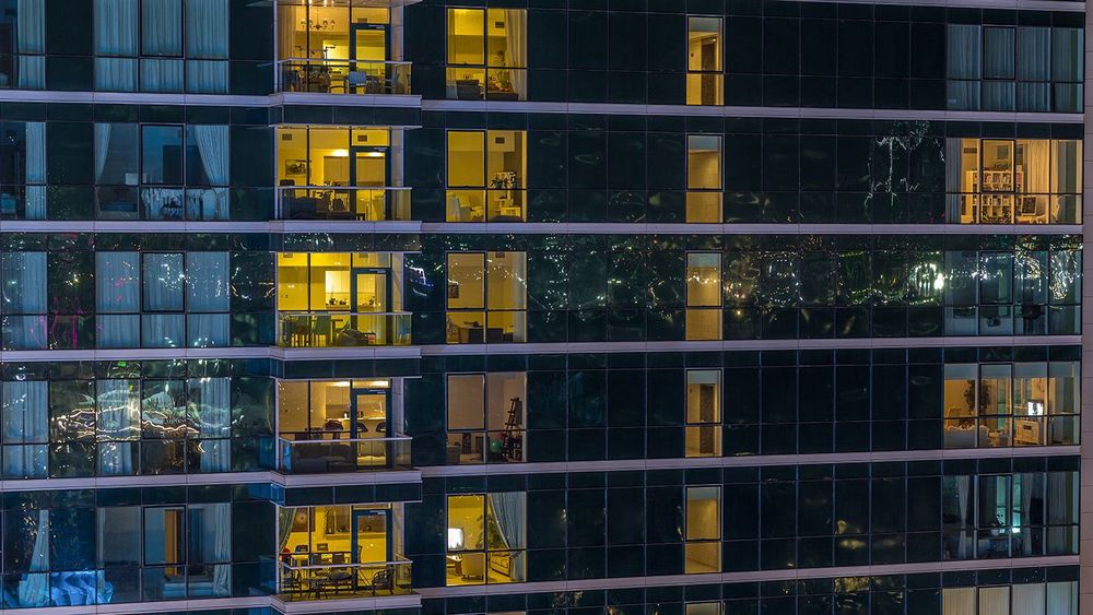 Glowing apartment windows at night in glass skyscraper timelapse