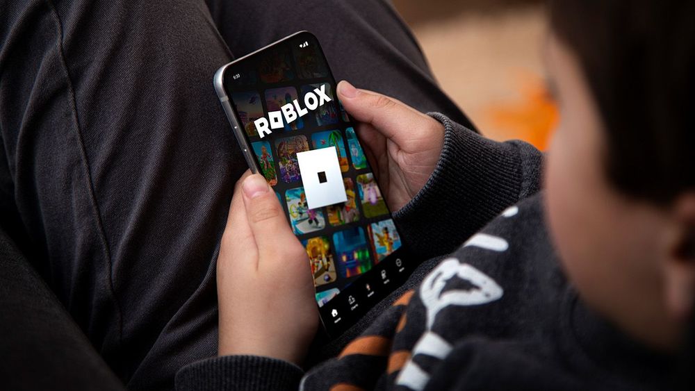 Little boy playing Roblox game on a mobile phone. Roblox is a ve