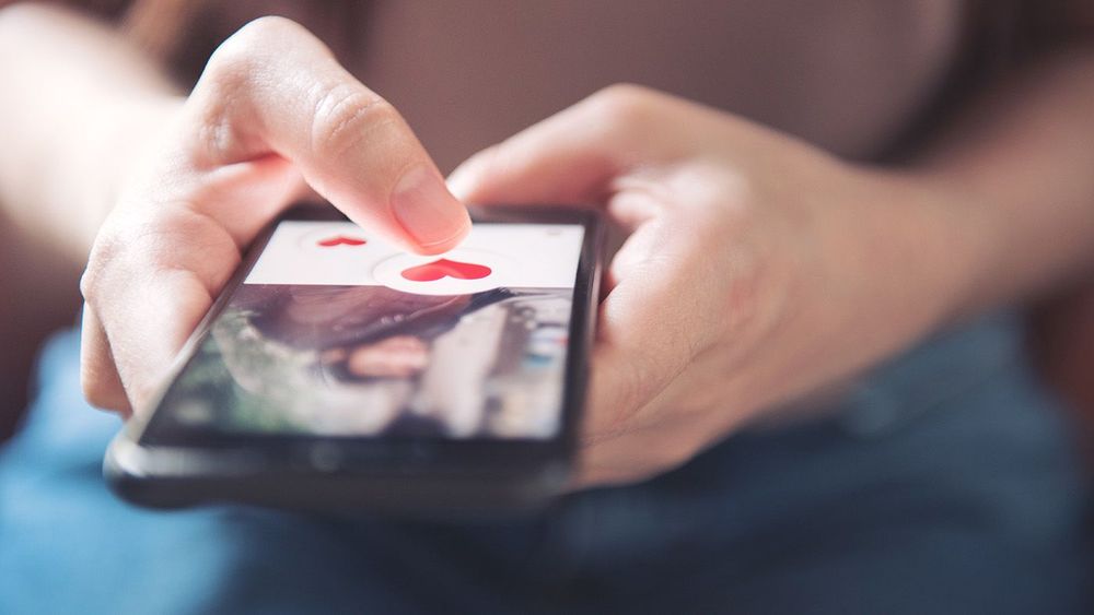 Finger of woman pushing heart icon on screen in mobile smartphon