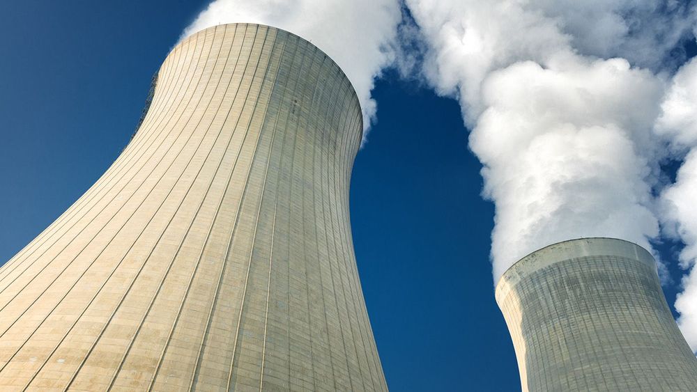 power plant cooling towers steaming on dark blue sky background