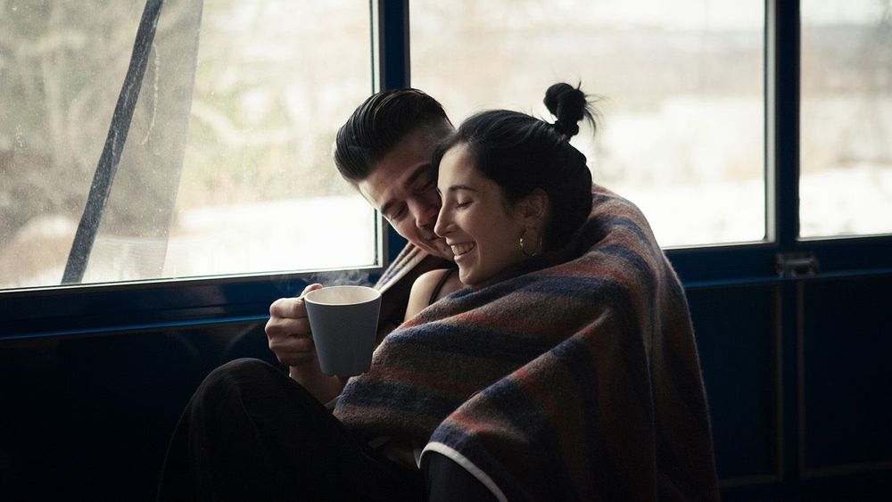 Happy boyfriend romancing with girlfriend while holding mug in b