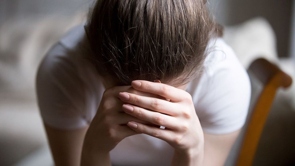 Close up desperate woman sitting on chair crying at home
