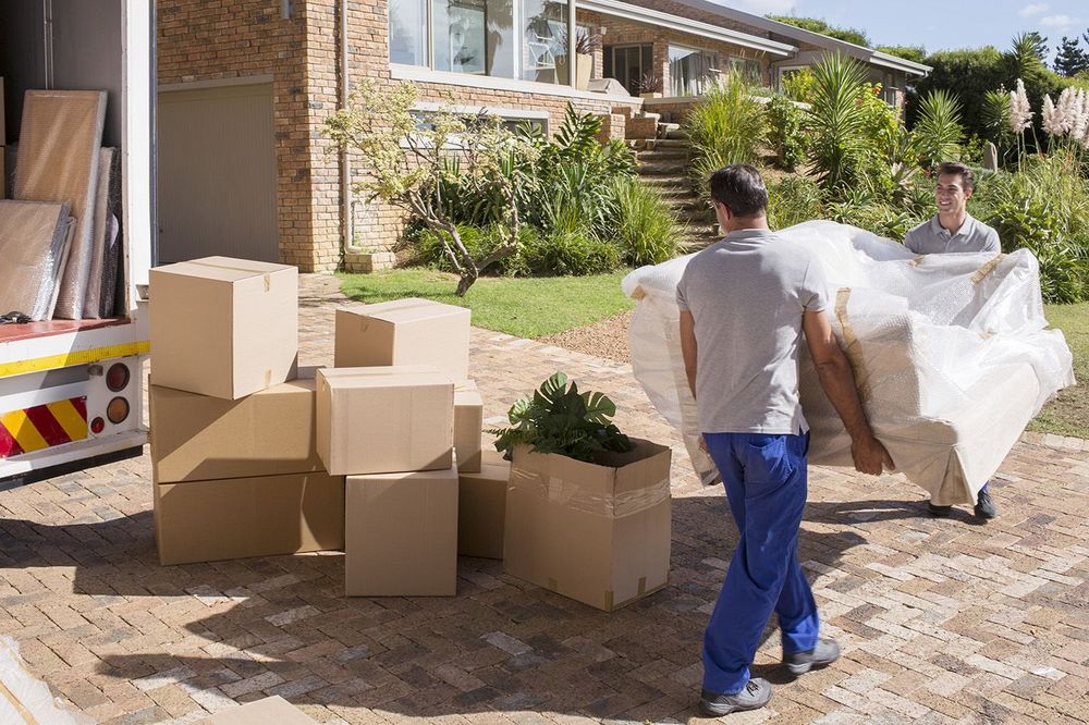 Movers carrying sofa from moving van to house