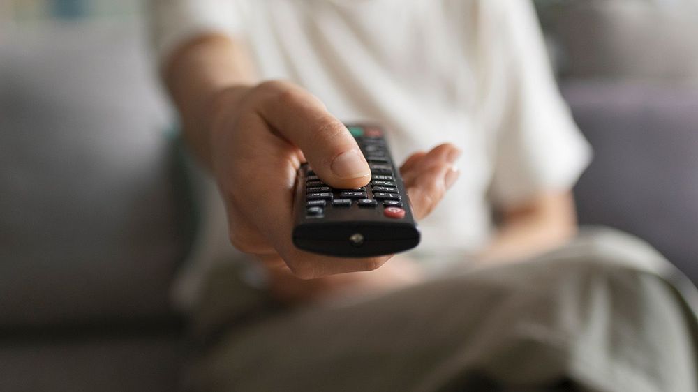 Woman watching TV and holding the remote control
