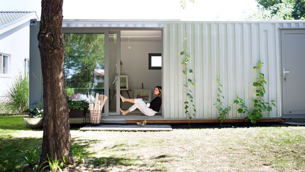 Mature woman working in home office in container house in backyard, resting.