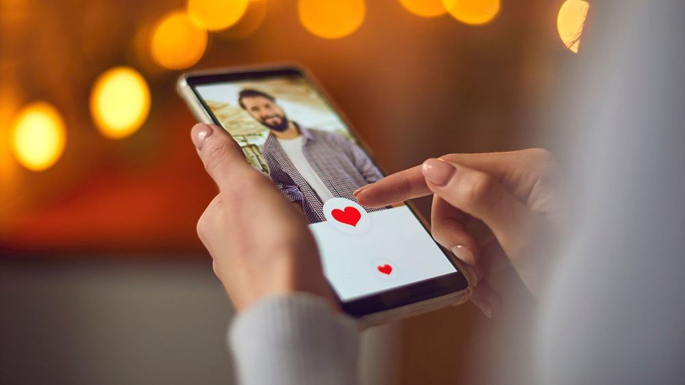 Closeup of woman looking at young man's profile photo on dating app and pressing like button
