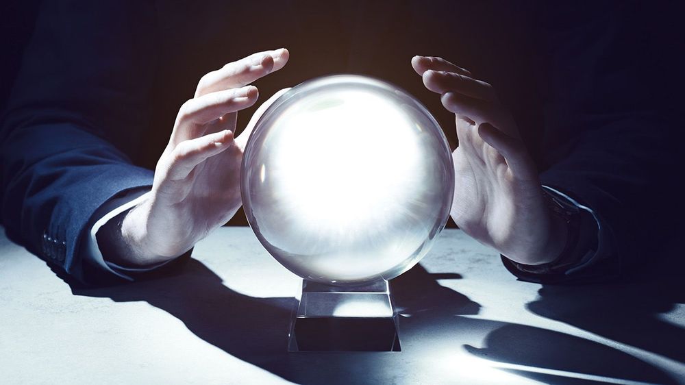 Businessman using crystal ball to predict future at table in dar
