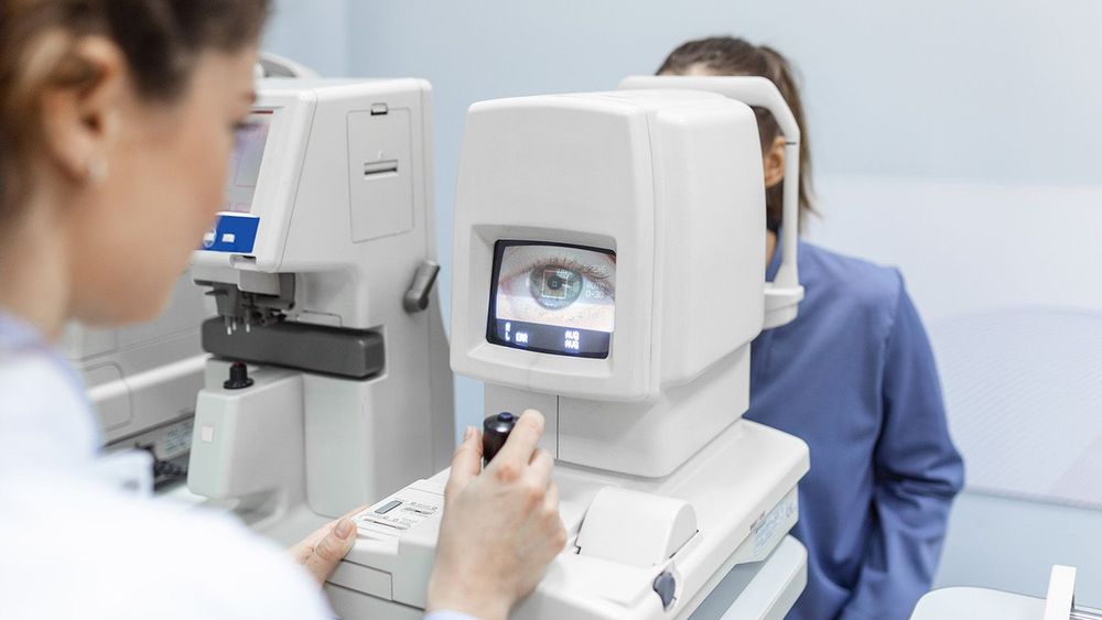 Doctor testing for eyes with special optical apparatus in modern clinic. Ophthalmologist examining eyes of a patient using digital microscope during a medical examination in the ophthalmologic office