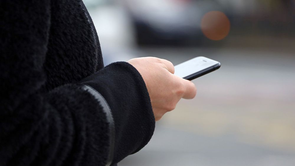Female hands with smartphone close up on blurred cars background