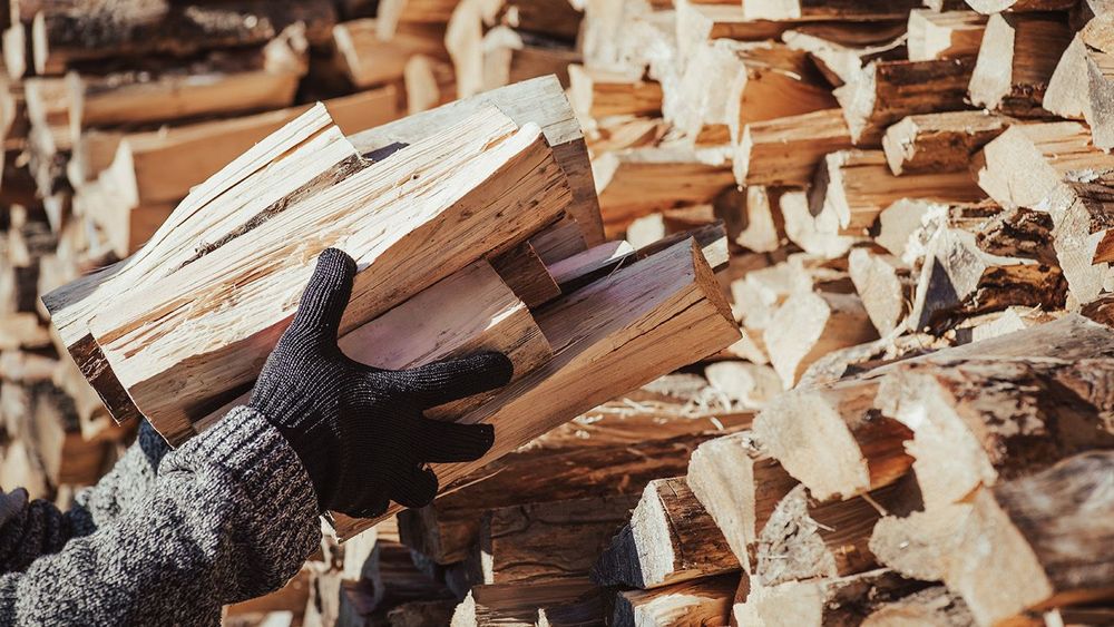 Close up of man takes firewood from pile, toned image. Using firewood for heating home in winter
