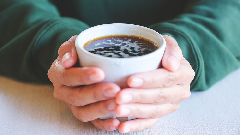 Closeup image of a woman holding a cup of hot coffee
