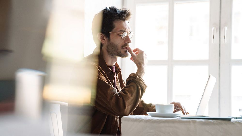 Image of handsome serious man using laptop while sitting