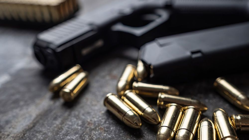 Hand gun with ammunition on dark background.