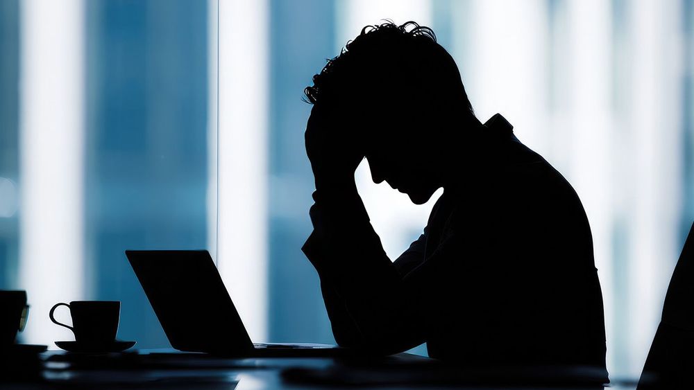 Silhouette of stressed businessman at desk
