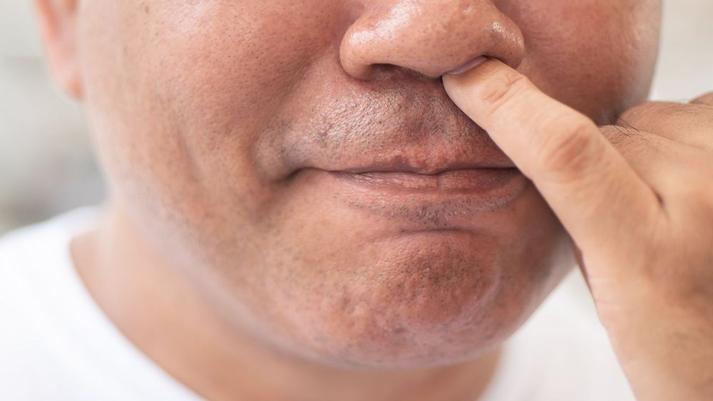 man picking his nose with nasty, dirty habit; concept of nose picking, unhealthy habit, bad manner with nose wax